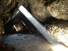 the light shines brightly through an opening in a rock cave with water coming from it