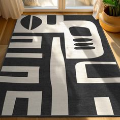 a black and white area rug in front of a window with potted plants on the floor