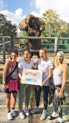 four people standing in front of an elephant statue holding a sign that says happy birthday