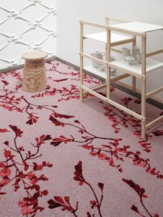 a pink rug with red flowers on it in a room next to a white wall