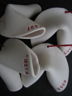 four white ceramic ornaments with red string and words that say joy, wish, laugh