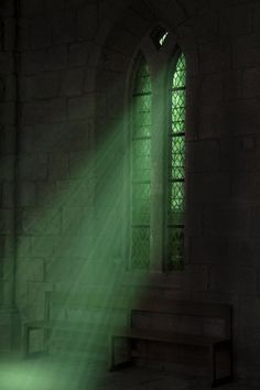 sunlight shining through the window into a dark room with stone steps and stained glass windows