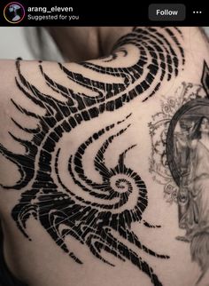 the back of a woman's shoulder with an intricate tattoo design on her left side