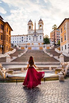 a woman in a red dress is sitting on some steps and looking at the building