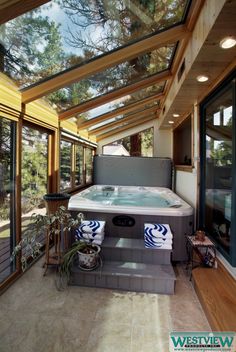 an indoor hot tub in the middle of a room with windows on both sides and skylights above it