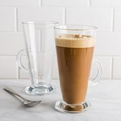 there is a cup of coffee on the table next to another glass with liquid in it