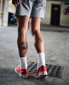 a person with tattoos standing on a skateboard