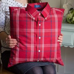 a woman sitting on a chair holding a red pillow with a plaid shirt on it