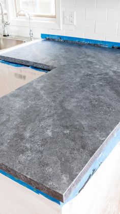 a kitchen counter top with blue tape on it and a sink in the back ground