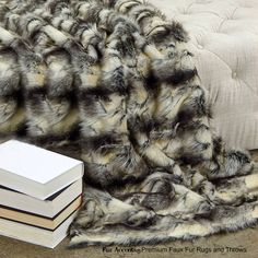 a pile of books sitting on top of a bed next to a fur covered blanket