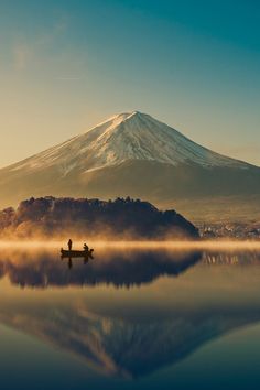 a person on a boat in the water with a mountain in the backgroud