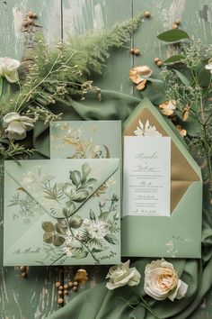 the wedding stationery is laid out with flowers and greenery