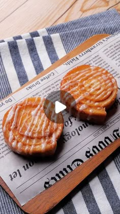 two pieces of food sitting on top of a wooden cutting board next to a blue and white towel