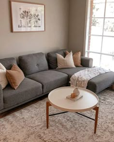 a living room with a couch, coffee table and rug in front of a window