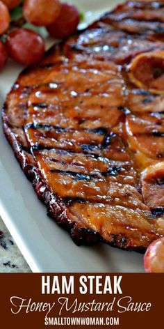 grilled ham steak on a white plate with grapes