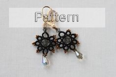 a pair of black and gold beaded earrings with crystal tears on the end