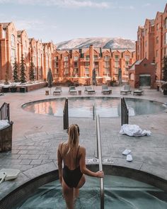 a woman in a black swimsuit standing next to a hot tub