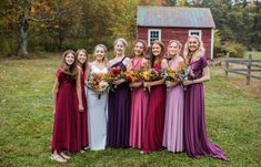 a group of women standing next to each other in front of a red barn with flowers