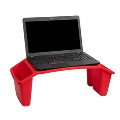 a laptop computer sitting on top of a red plastic table with two cups underneath it