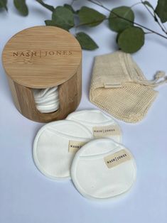 three cloth pads and two wooden box with labels on them sitting next to some green leaves