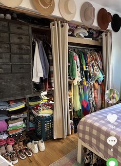 a bedroom with lots of hats and clothes on the shelves above the bed, along with an open closet