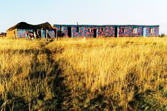 an abandoned building in the middle of a field with grass growing on it's sides