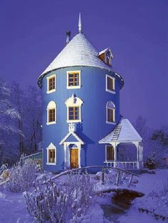 a large blue house with white trim and windows in the snow covered yard at night