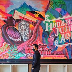 a man standing in front of a large mural