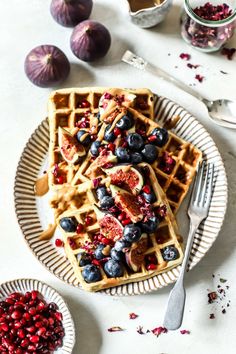 a waffle topped with blueberries and other toppings on a plate next to some fruit