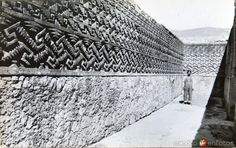 an old black and white photo of a man standing next to a wall