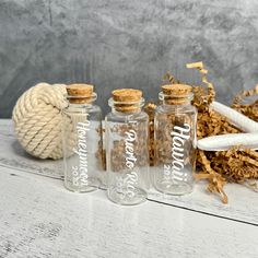 three glass bottles sitting on top of a wooden table next to rope and wood shaving