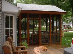 a dog is laying on the wooden deck in front of a gazebo with glass doors