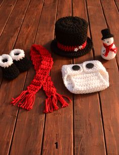 crocheted hats and scarves are laid out on a wooden table with snowmen