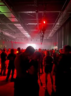 a group of people standing in a large room with red lights on the ceiling and floor