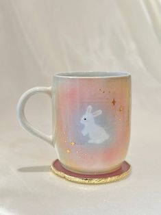 a coffee cup with a white rabbit painted on the side and gold trimmings