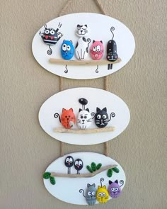 three white oval wall hangings with cats on them