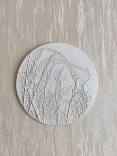 a white plaque with trees on it sitting on a wall in front of a beige background