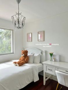 a teddy bear sitting on top of a bed next to a white desk and chair