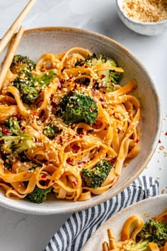 a bowl filled with noodles and broccoli next to chopsticks on a table