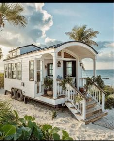 a tiny house on the beach with stairs leading up to it and palm trees in front