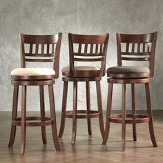 three barstools and stools in front of a wall