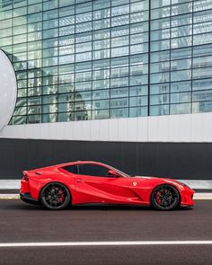 a red sports car parked in front of a large building