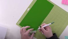 someone is cutting out a piece of green paper with scissors and a crayon pen