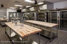 an industrial kitchen with stainless steel appliances and wooden tables