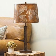 a lamp sitting on top of a wooden table next to a brown leather couch and pillow