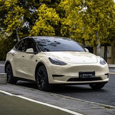 a white car is parked on the side of the road near some trees and bushes