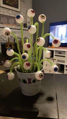 a potted plant with fake eyes on it sitting on a table in front of a tv