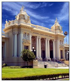 an ornate building with columns and pillars on the front lawn, under a partly cloudy blue sky