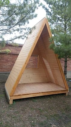 a wooden structure sitting on top of a grass covered field next to a brick wall