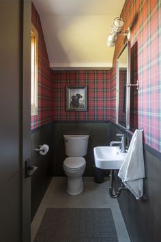 a bathroom with a toilet, sink and plaid wallpaper on the walls in it